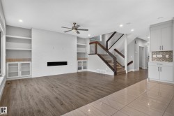 Built-in shelving, integrated fireplace, wood-finish flooring, glass panel staircase, and recessed lighting - 