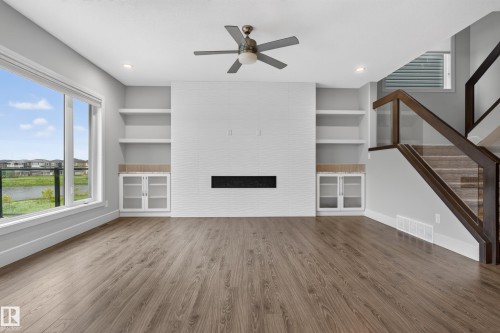 Wood-finish flooring, built-in shelving, glass-panel staircase, contemporary fireplace, and a ceiling fan - 2219 22 Street Nw, Edmonton, AB 