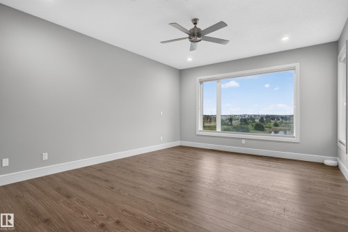 Spacious room featuring wood-finish flooring, a large window, recessed lighting, and a ceiling fan - 2219 22 Street Nw, Edmonton, AB 