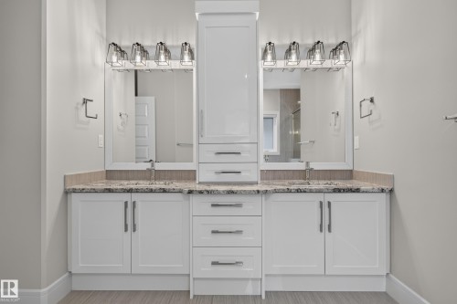 Dual vanity with white cabinetry, light-toned stone-finish countertop, and individual vessel sinks - 2219 22 Street Nw, Edmonton, AB 