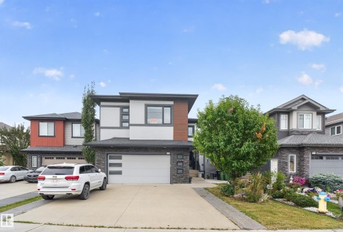 Contemporary exterior with stone veneer and horizontal siding accents, an attached garage, and a concrete driveway - 2219 22 Street Nw, Edmonton, AB 
