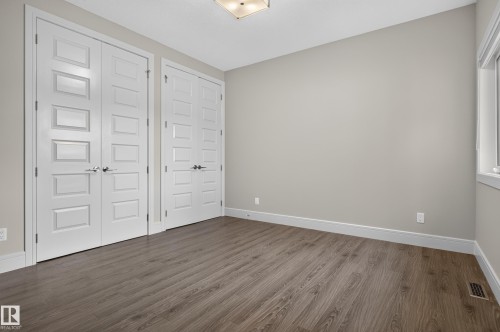 Spacious room featuring wood-finish flooring, light neutral wall tones, white trim, and a window for natural light - 2219 22 Street Nw, Edmonton, AB 