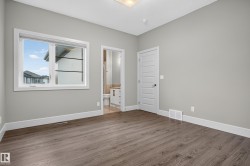 Wood-finish flooring, light gray wall color, white trim, and a white interior door - 