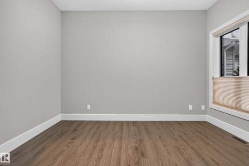 Bright, light-filled room featuring pristine white walls, white crown molding, and warm wood-finish flooring throughout - 2219 22 Street Nw, Edmonton, AB 