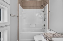 White shower/tub combination with a curved shower rod and a hand-held shower head - 