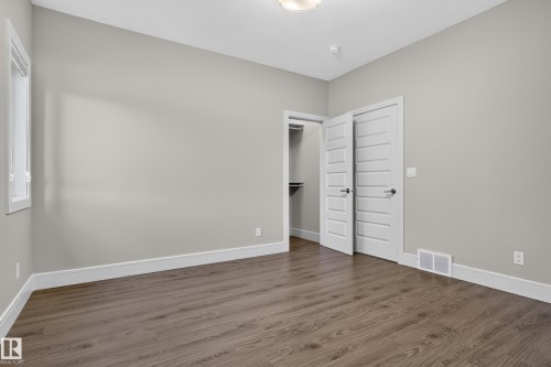 Wood-finish flooring, white trim, flat panel interior doors, and a closet with shelving - 2219 22 Street Nw, Edmonton, AB 