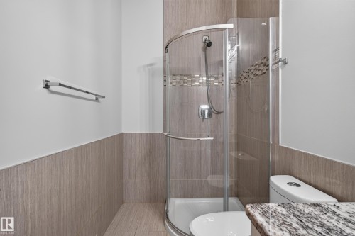 Tiled shower enclosure with a mosaic accent band, curved glass door, and chrome shower fixtures - 2219 22 Street Nw, Edmonton, AB 