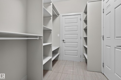 Walk-in closet featuring extensive built-in shelving, hanging rods, and tile flooring - 2219 22 Street Nw, Edmonton, AB 