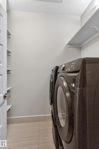 Laundry area featuring tile flooring, built-in shelving, and light gray walls - 2219 22 Street Nw, Edmonton, AB 