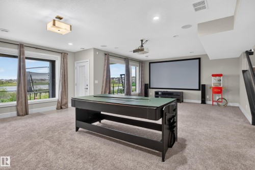 Spacious entertainment area featuring a large projection screen, recessed lighting, and carpeted flooring - 2219 22 Street Nw, Edmonton, AB 