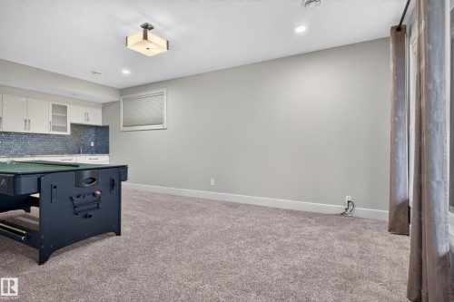 Wet bar with high-gloss cabinetry, mosaic tile backsplash, and undermount sink - 2219 22 Street Nw, Edmonton, AB 
