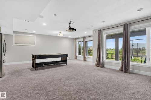 Spacious entertainment area with recessed lighting, large windows, wall-to-wall carpeting, and a ceiling-mounted projector - 2219 22 Street Nw, Edmonton, AB 