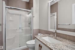 Shower with sliding glass enclosure, vanity with stone countertop, undermount sink, and wall-mounted mirror - 