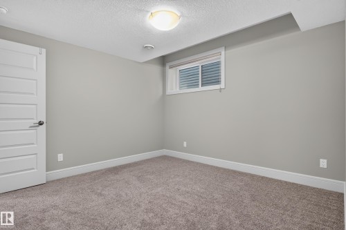 Neutral wall color, carpet flooring, a white paneled door, window with blinds, and flush mount lighting - 2219 22 Street Nw, Edmonton, AB 