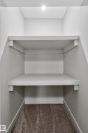 Built-in shelving with two levels, recessed ceiling light, and neutral-toned carpet - 