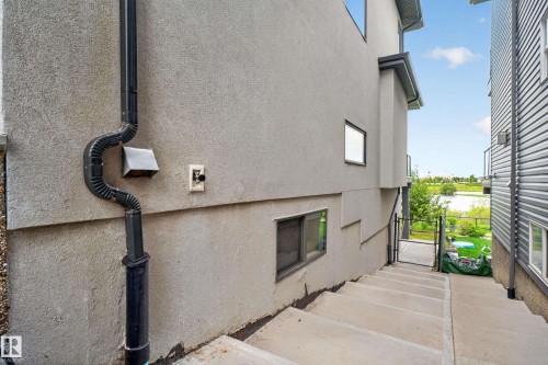 Exterior stucco finish with a rain gutter system, concrete steps, and a chain-link gate - 2219 22 Street Nw, Edmonton, AB 