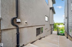 Exterior stucco finish with a rain gutter system, concrete steps, and a chain-link gate - 