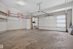 Spacious garage with concrete flooring, overhead garage door with integrated windows, built-in shelving, and a pedestrian access door - 