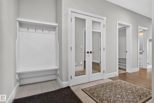 Built-in hall tree with bench, French doors with glass panels, wood-finish flooring, and light-toned wall paint - 2219 22 Street Nw, Edmonton, AB 