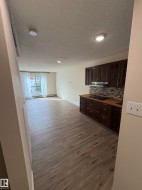 Wood-finish flooring throughout, dark wood cabinetry, mosaic tile backsplash, built-in cooktop, and recessed lighting - 