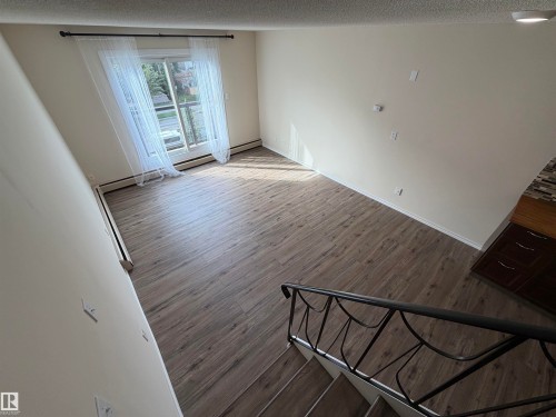 Wood-finish flooring, sliding glass door, balcony, decorative metal railing, and built-in cabinetry with a tiled backsplash - #209 11429 124 St Nw, Edmonton, AB 