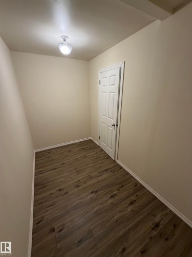 Wood-finish flooring, neutral wall tones, white trim, paneled door, and ceiling-mounted light fixture - #209 11429 124 St Nw, Edmonton, AB 
