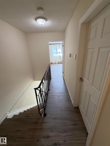 Wood-finish flooring, white paneled door, and a black wrought iron railing - #209 11429 124 St Nw, Edmonton, AB 