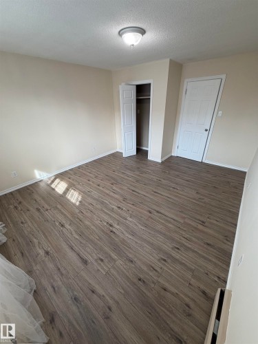 Wood-finish flooring throughout, neutral wall tones, and a built-in closet with bi-fold doors - #209 11429 124 St Nw, Edmonton, AB 