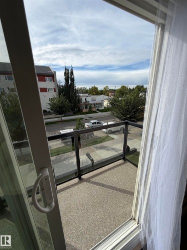 Sliding glass door opening to a balcony with a glass and metal railing - #209 11429 124 St Nw, Edmonton, AB 