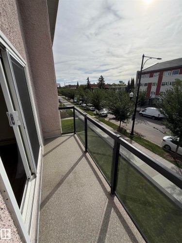 Private balcony featuring a textured concrete surface and glass panel railing - #209 11429 124 St Nw, Edmonton, AB 