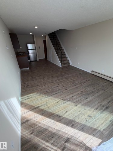 Wood-finish flooring throughout, stainless steel refrigerator, dark wood-finish cabinetry, and recessed lighting - #209 11429 124 St Nw, Edmonton, AB 