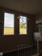 Two vertical windows with white trim, modern multi-bulb chandelier, and metal staircase railing - 