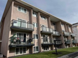 Multi-level building with stucco exterior, multiple units featuring individual balconies with glass railings, and expansive windows - 