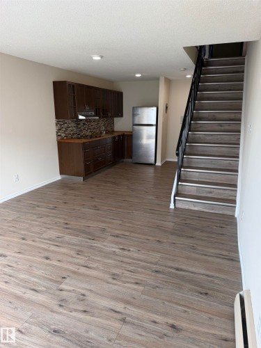 Well-appointed kitchen featuring dark wood cabinetry, mosaic tile backsplash, and stainless steel appliances - #209 11429 124 St Nw, Edmonton, AB 