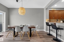 Open dining area featuring wood-finish flooring, a contemporary ceiling light fixture, and direct access to an exterior space through a sliding glass door - 