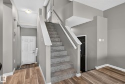 Central carpeted staircase with white railings, complemented by wood-finish flooring - 