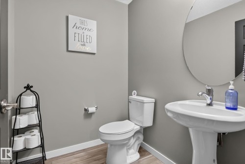 Pedestal sink with chrome faucet and circular mirror - 385 Simmonds Way, Leduc, AB - Indoor Photo Showing Bathroom