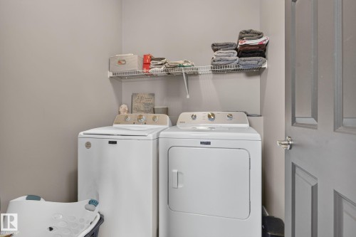 Dedicated laundry area featuring a wire storage shelf, light gray wall paint, and a paneled interior door with a brushed nickel handle - 385 Simmonds Way, Leduc, AB - Indoor Photo Showing Laundry Room