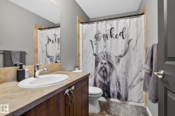 Full bathroom with a wood-finish vanity, integrated sink, and an expansive mirror - 
