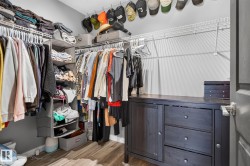 Walk-in closet featuring wood-finish flooring, white wire shelving, grey walls, and a dark wood-finish built-in dresser with drawers and cabinet storage - 