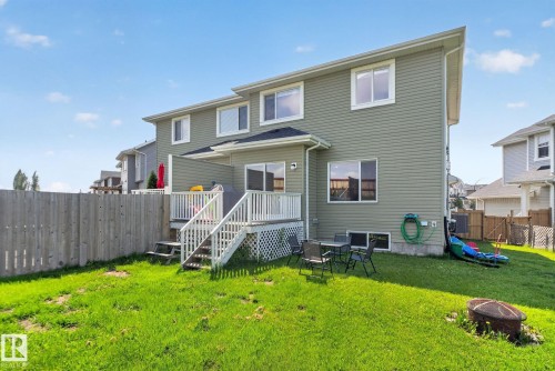 Expansive backyard featuring a green lawn, wood fence, and a multi-level deck with white railings and steps - 385 Simmonds Way, Leduc, AB - Outdoor With Exterior