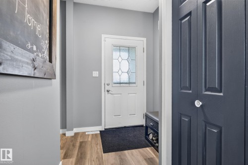 Entryway featuring wood-finish flooring, light gray walls, and a white paneled door with decorative glass inserts - 385 Simmonds Way, Leduc, AB -  Photo Showing Other Room