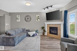 Living space featuring a tiled fireplace with a classic white mantel, wood-finish flooring, and a large window - 