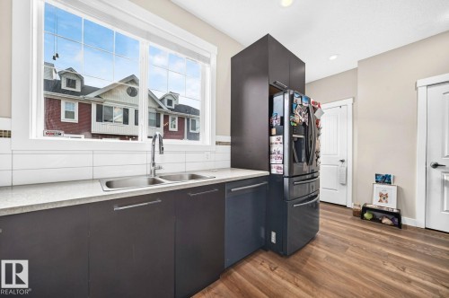 Dual basin stainless steel sink, tile backsplash, wood-finish flooring, recessed lighting, and white paneled doors - #20 8315 180 Av Nw, Edmonton, AB 