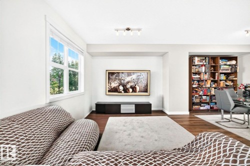 Recessed wall for media, wood-finish flooring, built-in shelving, white trim window, and overhead track lighting - #20 8315 180 Av Nw, Edmonton, AB 