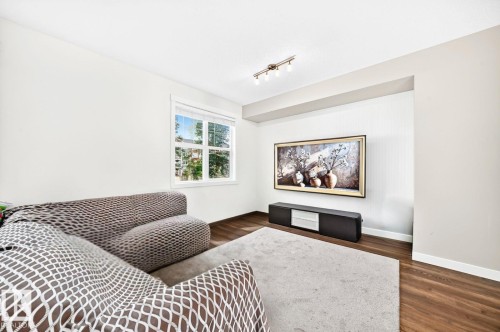 Recessed media wall, track lighting, wood-finish flooring, white trim, and a white framed window - #20 8315 180 Av Nw, Edmonton, AB 