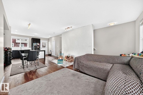 Wood-finish flooring throughout, with a dining area featuring a modern table and seating - #20 8315 180 Av Nw, Edmonton, AB 