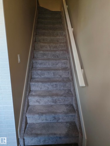 Carpeted staircase with a white handrail and neutral wall tones - #20 8315 180 Av Nw, Edmonton, AB 