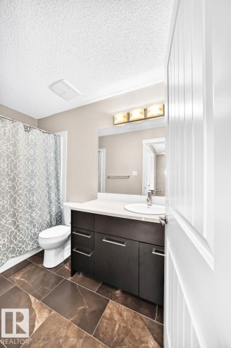 Dark wood-finish vanity with a light countertop, integrated sink, and chrome fixtures - #20 8315 180 Av Nw, Edmonton, AB 