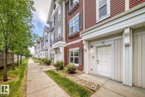 Townhome exterior with a paneled entry door, overhead portico, and decorative window boxes - #20 8315 180 Av Nw, Edmonton, AB 